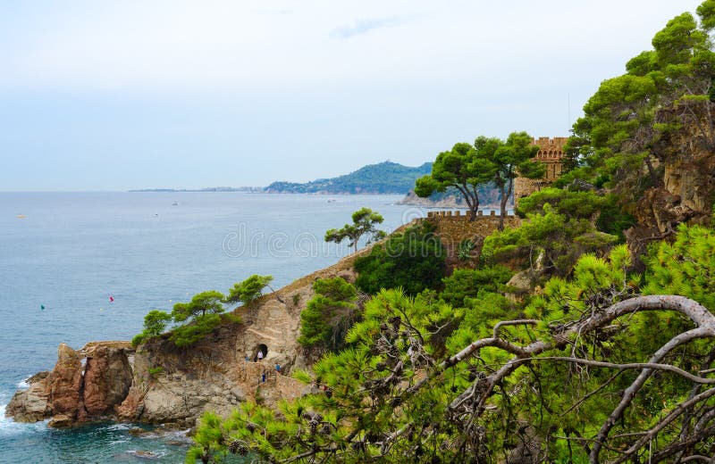 岩石海岸和城堡美丽的景色由海滩，略雷特德马尔，布拉瓦海岸，西班牙 库存照片